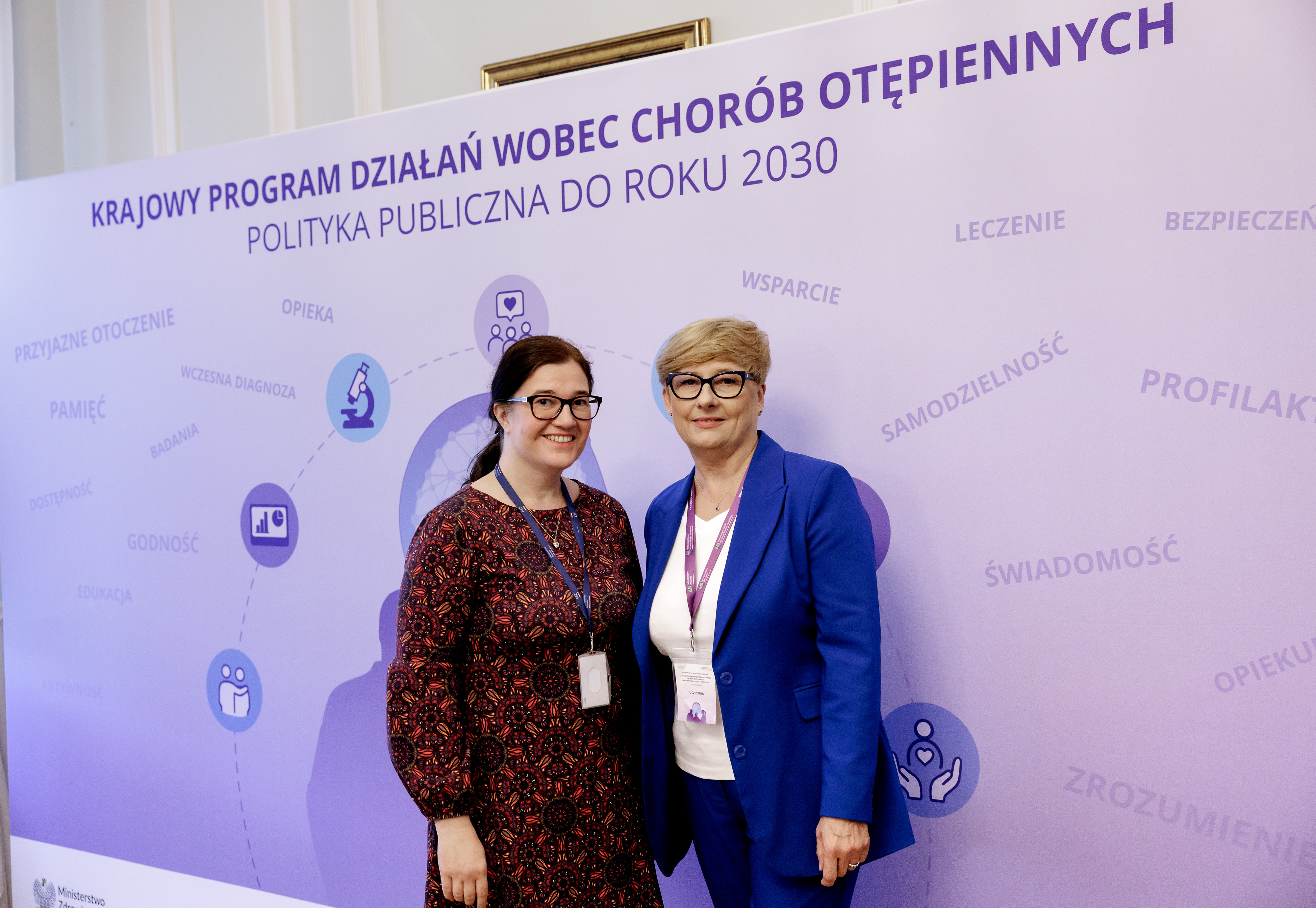 Zdjęcie na tle baneru "Karjowy program działa  wobec chorób otępiennych stoją - pierwsza Małgorzata Michalska i prof. Małgorzata Sobieszczańska