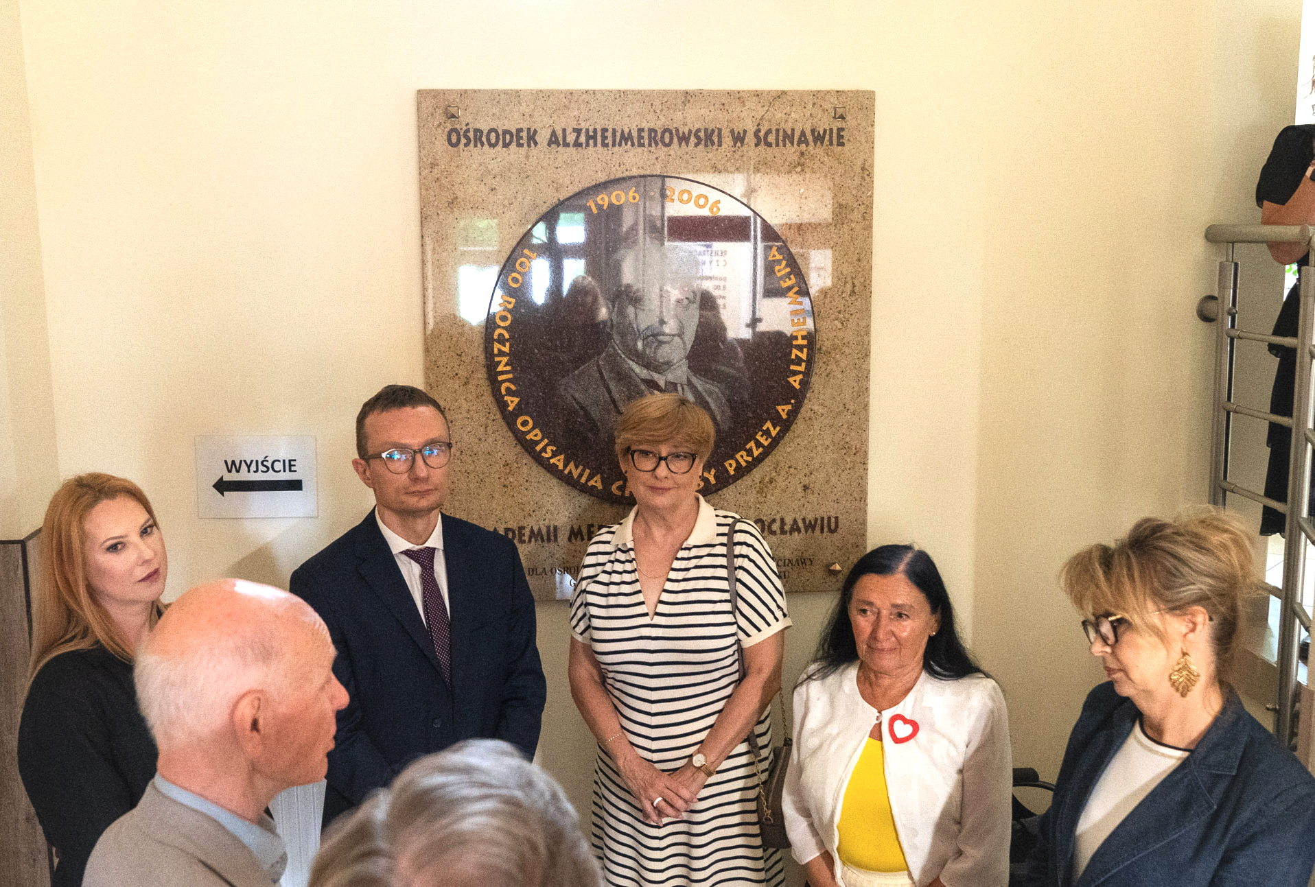 tablica ośrodek Alzhelmerowski w Ścinwie z sześcioma osobami na zdjęciu